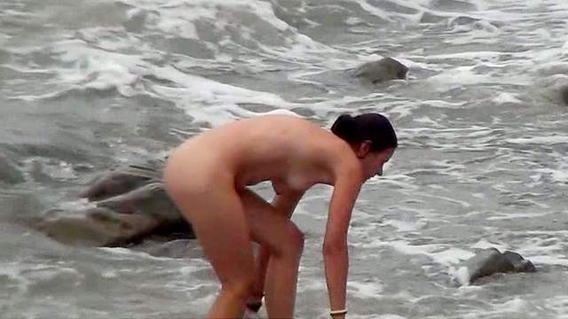 Tanned nudist is walking on the beach