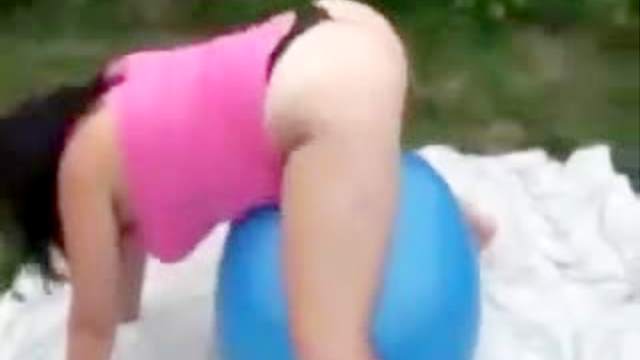 Fat girl on exercise ball outdoors