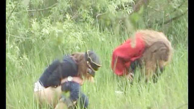 Two girls go pee in a field