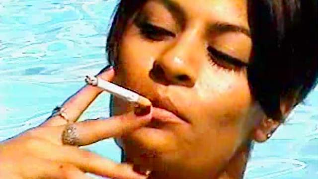 Latina smokes and catches sun outdoors