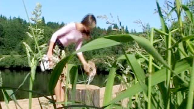 Girl pisses in the dirt by the lake