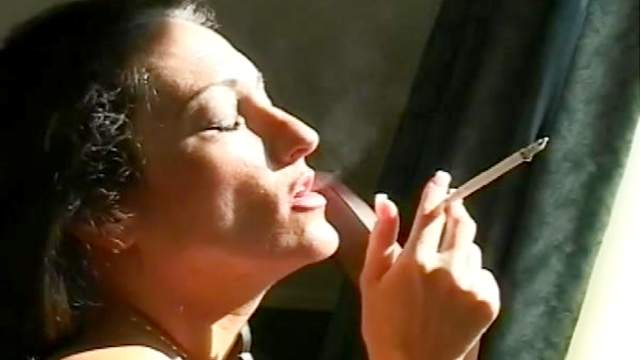 Brunette with sexy face smokes a cigarette with pleasure