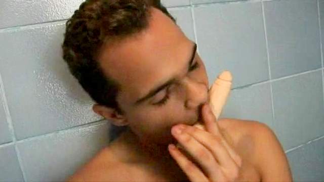 Skinny dude is lying and sucking his dildo